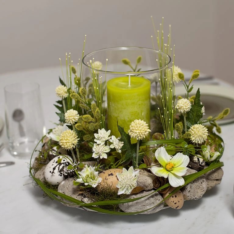 Frühlingshaftes Tischgesteck mit Kerze, Wachteleiern und weißen Blüten
