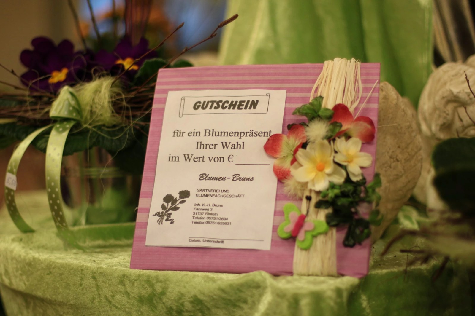 Gutschein für ein Blumenpräsent in rosa Umschlag mit Blüten und Schmetterling