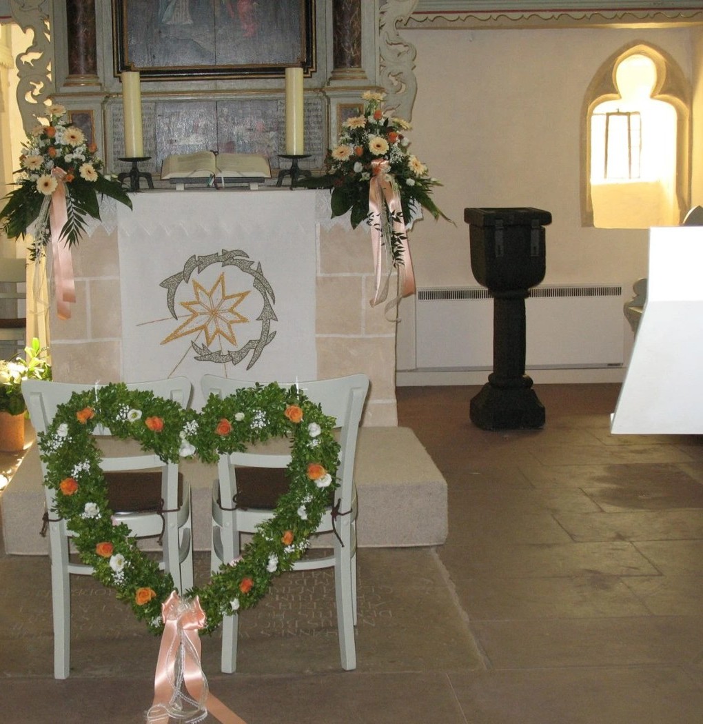 Kirchenschmuck mit Altarsträußen und Herz aus Buchsbaum auf den Brautstühlen