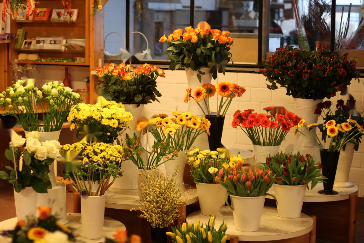 Frische Schnittblumen in weißen Vasen und Eimern: Rosen, Gerbera, Tulpen und Chrysanthemen