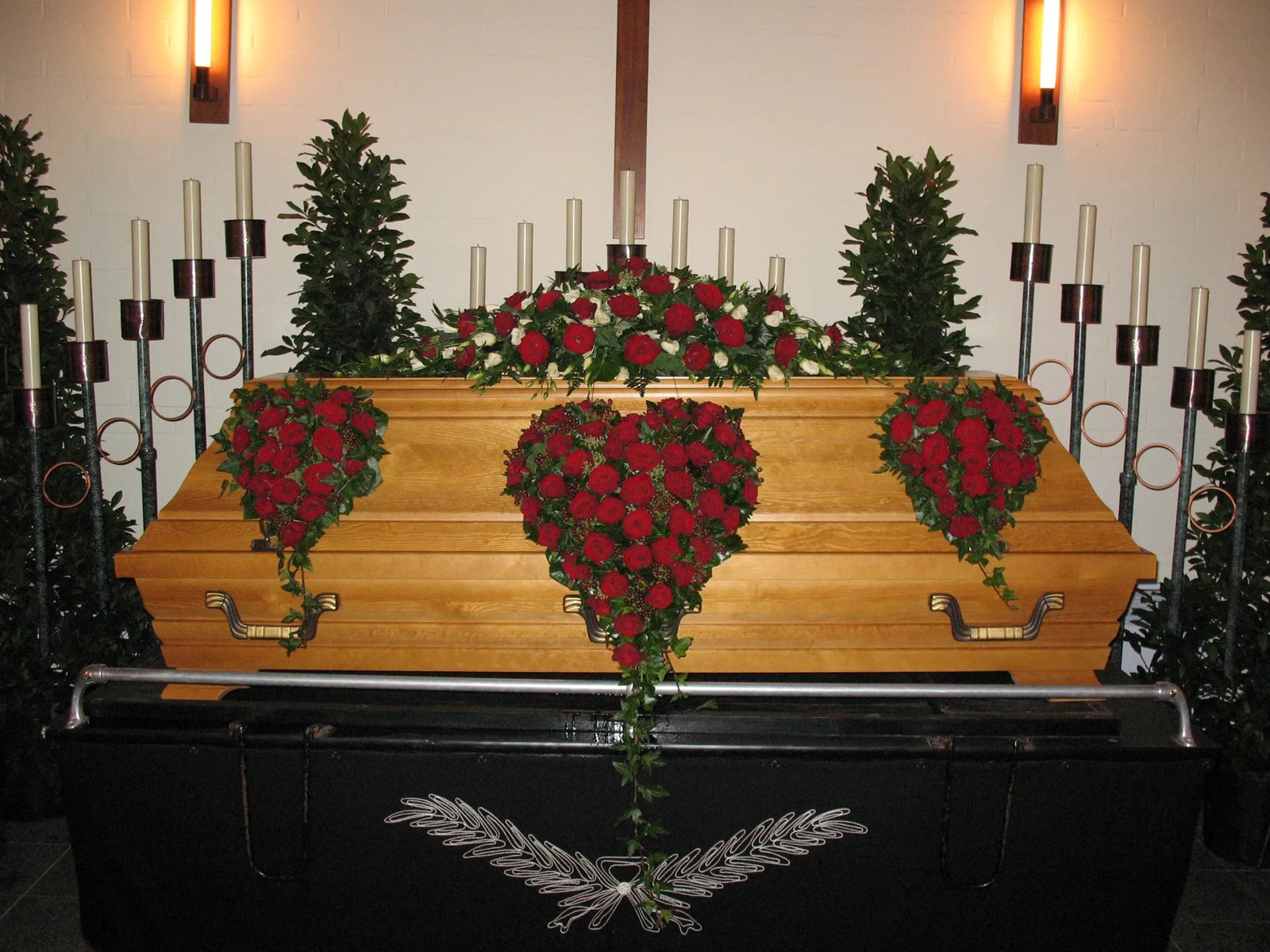 Sargschmuck aus roten Rosen in Herzform mit Efeu