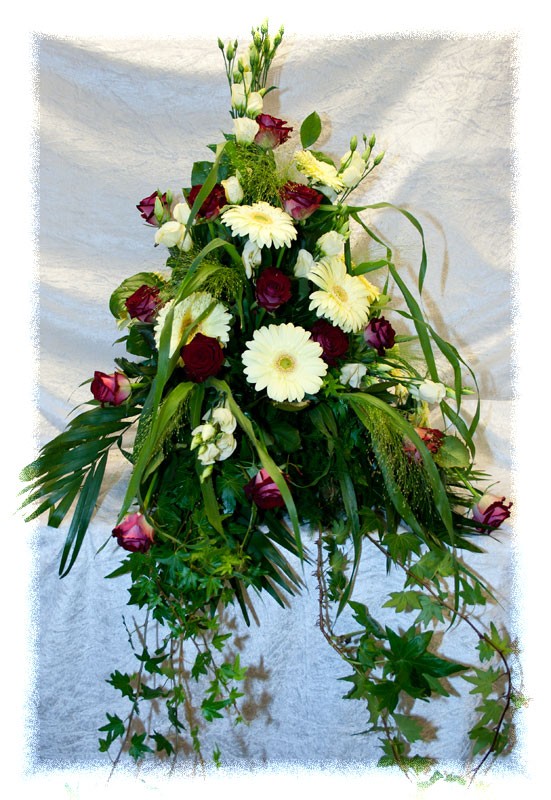 Gesteck mit roten Rosen, weißen Gerbera und Efeuranken